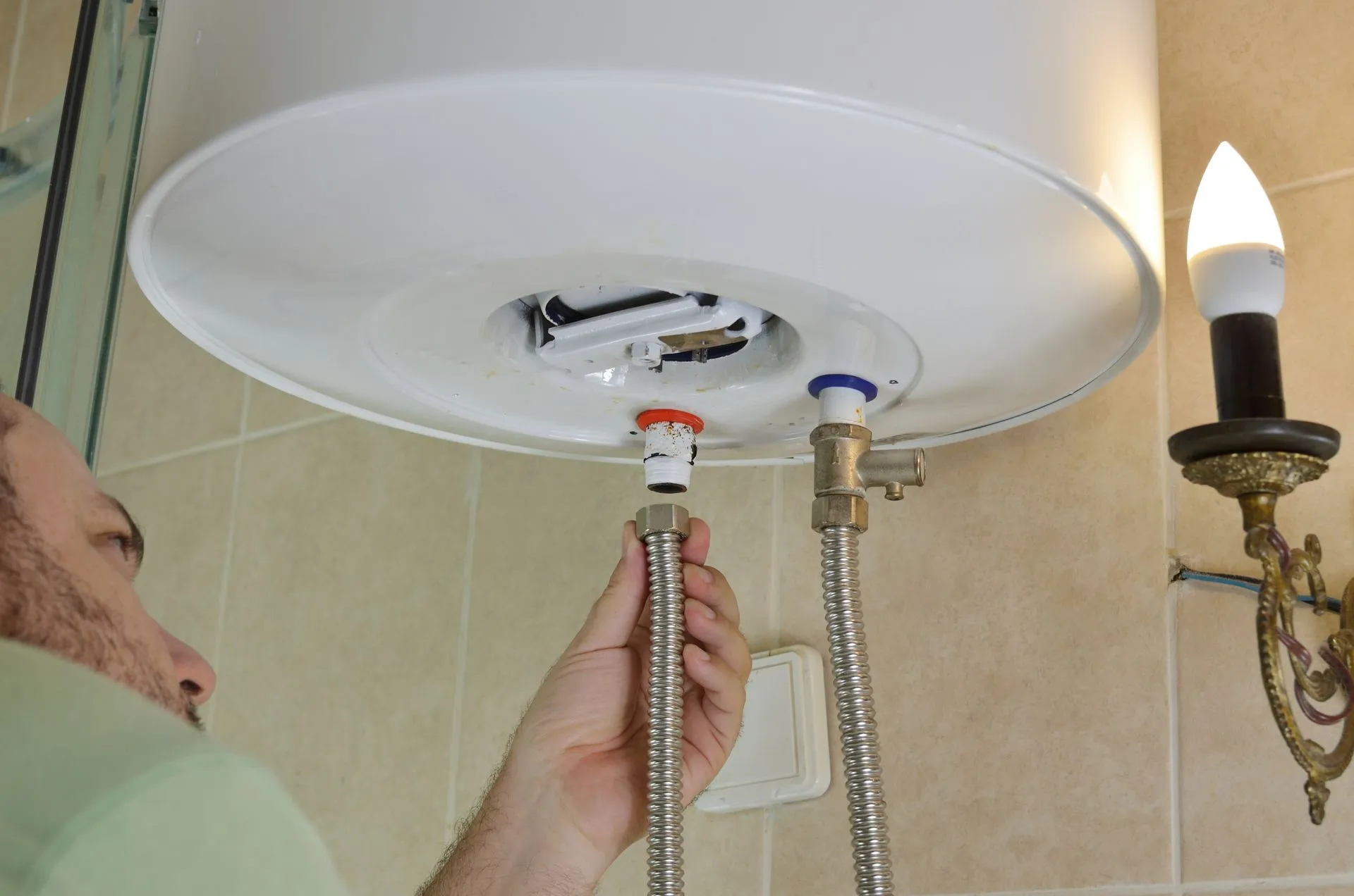 A person is fixing a water heater in a bathroom