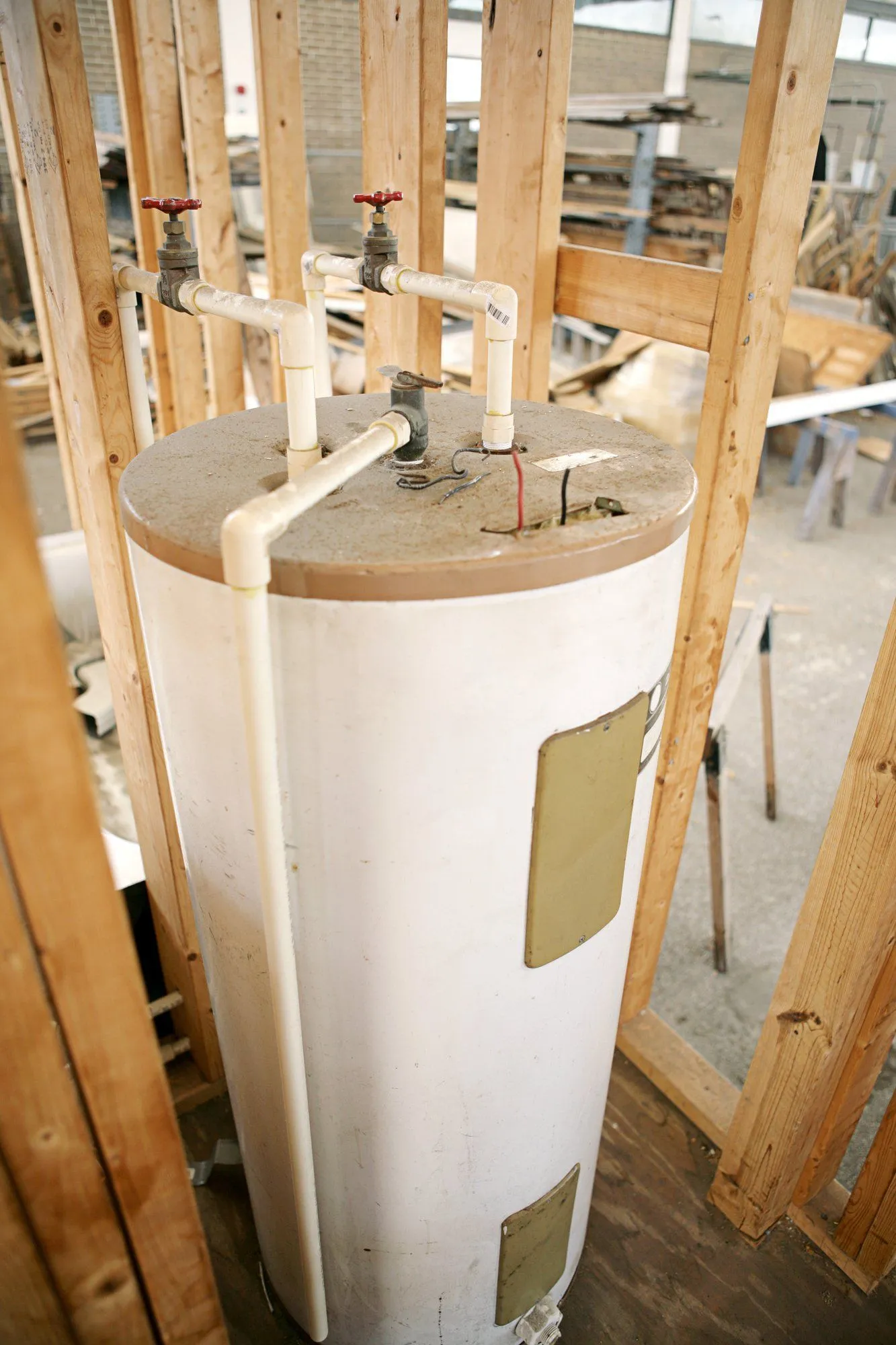 A water heater is sitting inside of a house under construction.